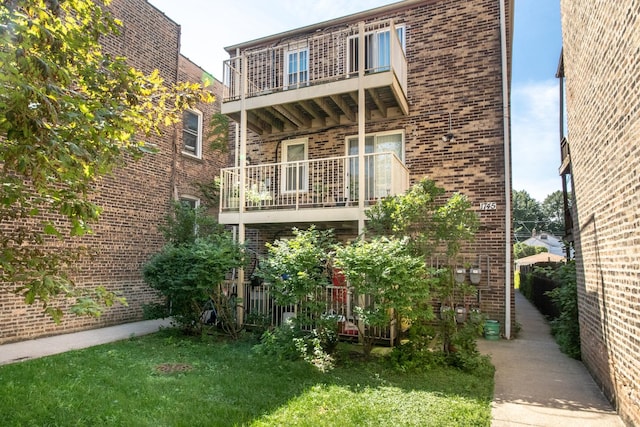 rear view of property with a lawn and a balcony