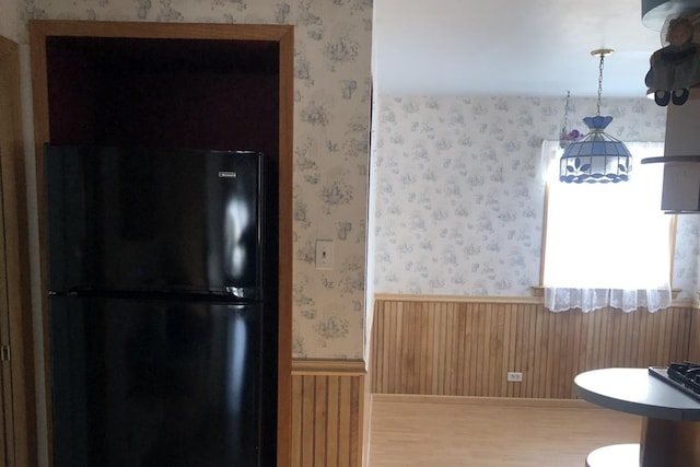 interior space featuring wood walls and black refrigerator