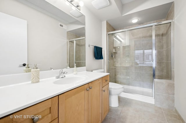 bathroom featuring tile patterned flooring, vanity, a shower with door, and toilet