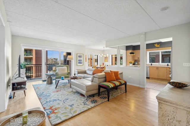 living room with a notable chandelier, sink, a textured ceiling, and light hardwood / wood-style flooring