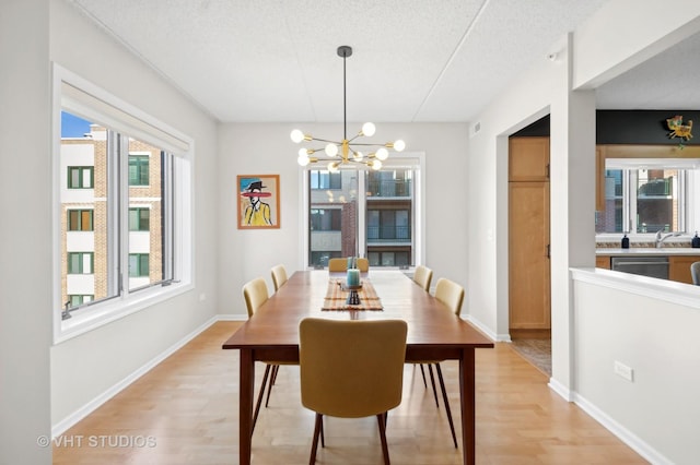 dining room featuring light hardwood / wood-style floors, sink, a textured ceiling, and a chandelier