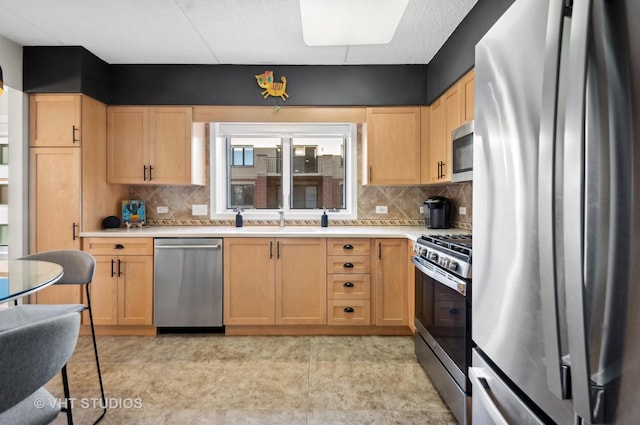 kitchen with decorative backsplash, light brown cabinetry, sink, and appliances with stainless steel finishes