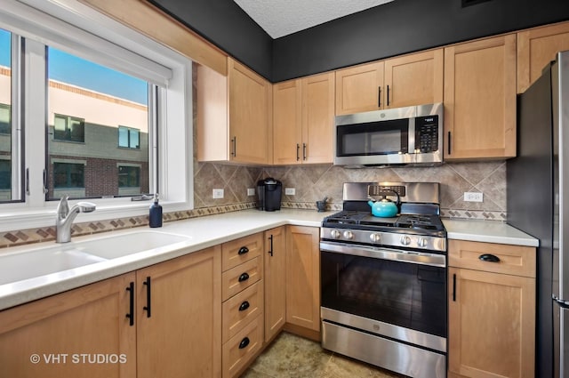 kitchen with decorative backsplash, sink, light brown cabinets, and appliances with stainless steel finishes