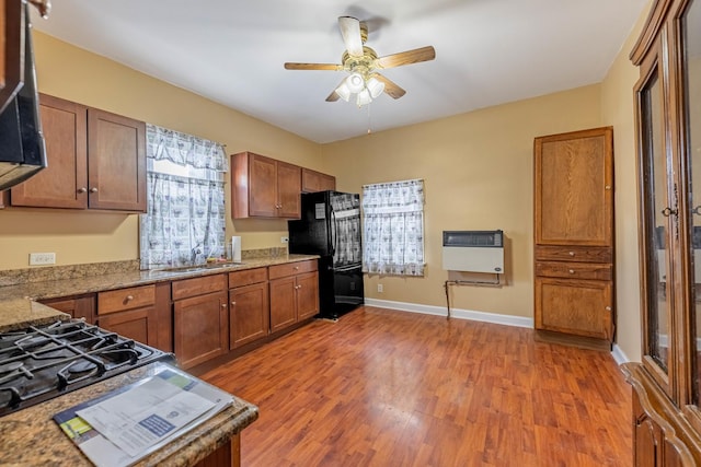 kitchen with ceiling fan, sink, heating unit, black refrigerator, and hardwood / wood-style flooring