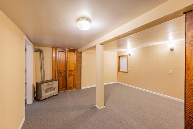 basement featuring wood walls, dark carpet, and a baseboard heating unit