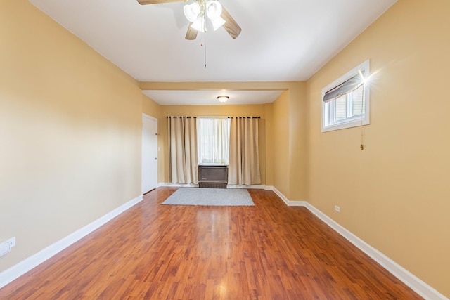 empty room with ceiling fan, wood-type flooring, and a wealth of natural light