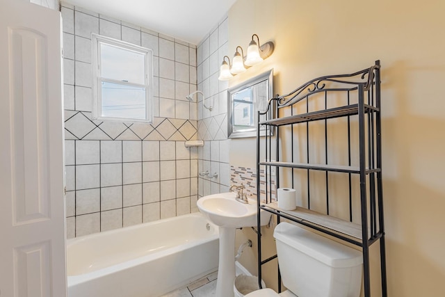 bathroom with tile patterned floors, toilet, and tiled shower / bath