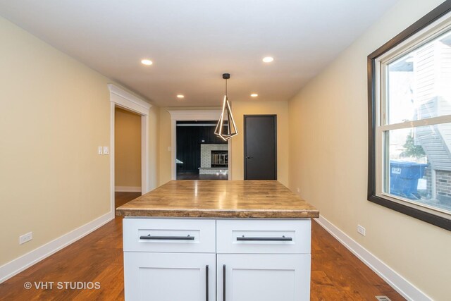 kitchen featuring decorative light fixtures, dark hardwood / wood-style flooring, white cabinetry, and a kitchen island