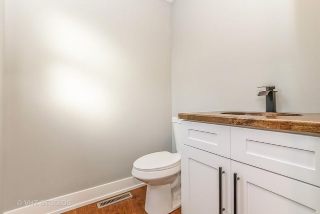 bathroom with hardwood / wood-style floors, toilet, and vanity