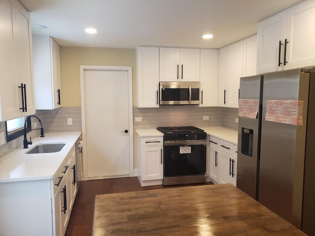 kitchen with dark hardwood / wood-style flooring, sink, white cabinetry, decorative backsplash, and stainless steel appliances