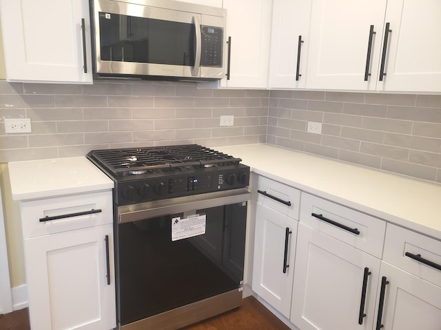 kitchen with white cabinets, gas stove, and tasteful backsplash