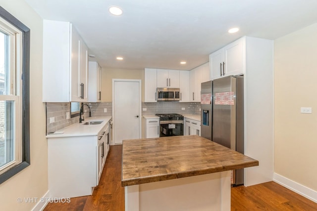 kitchen featuring white cabinets, appliances with stainless steel finishes, dark wood-type flooring, tasteful backsplash, and sink