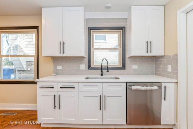 kitchen with tasteful backsplash, dishwasher, white cabinetry, sink, and a healthy amount of sunlight