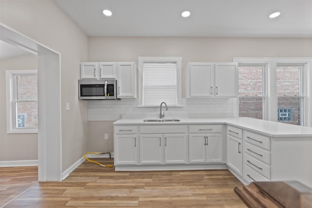 kitchen with sink, decorative backsplash, white cabinetry, and light wood-type flooring