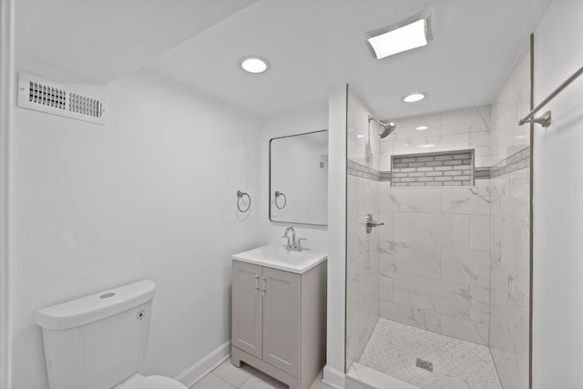 bathroom with tile patterned floors, a tile shower, vanity, and toilet