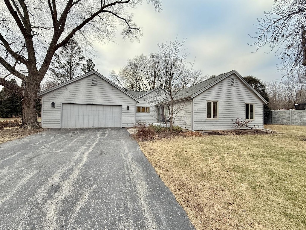 ranch-style home featuring a garage and a front lawn