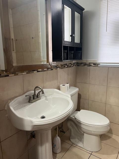 bathroom featuring tile patterned floors, sink, tile walls, and toilet