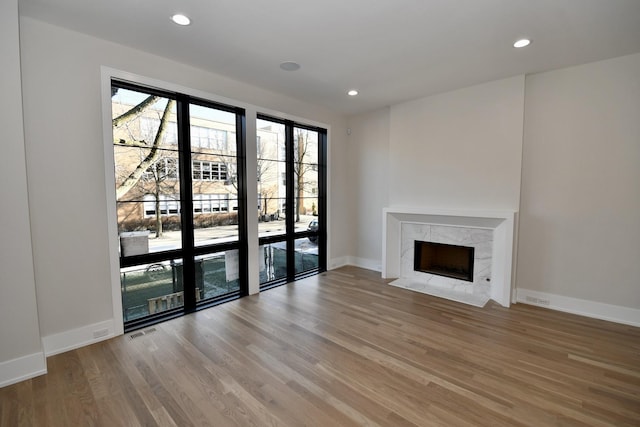 unfurnished living room with a high end fireplace and light hardwood / wood-style flooring