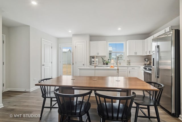 kitchen with stainless steel refrigerator with ice dispenser, a kitchen island, dark hardwood / wood-style flooring, and white cabinetry