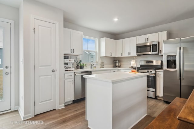 kitchen featuring stainless steel appliances, sink, white cabinetry, light hardwood / wood-style flooring, and a kitchen island