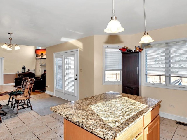 kitchen featuring light stone countertops, light tile patterned floors, hanging light fixtures, and an inviting chandelier