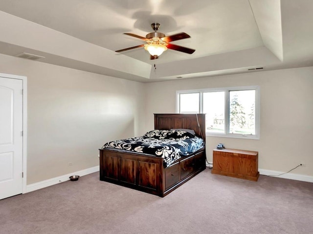 carpeted bedroom featuring ceiling fan and a tray ceiling