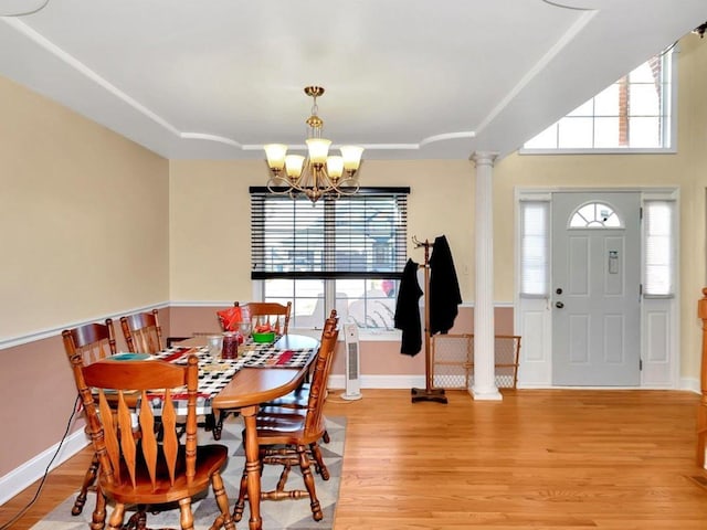 dining space featuring light hardwood / wood-style flooring, an inviting chandelier, a wealth of natural light, and decorative columns