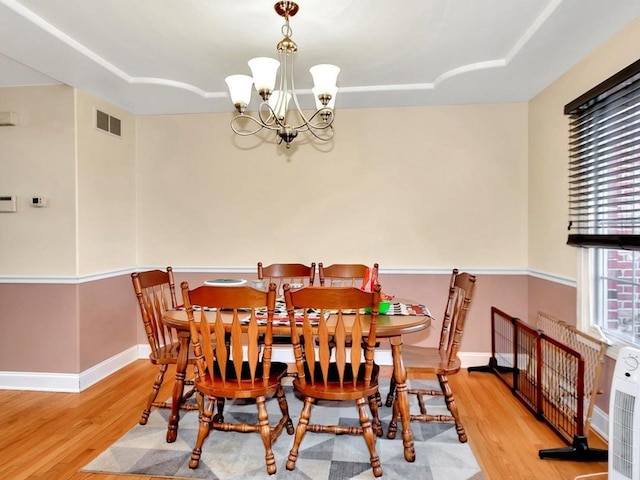 dining room with light hardwood / wood-style flooring and an inviting chandelier