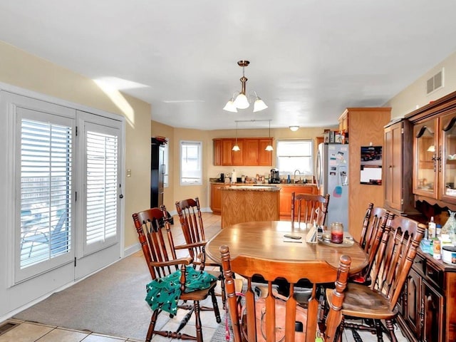 dining space featuring sink, light tile patterned flooring, and an inviting chandelier