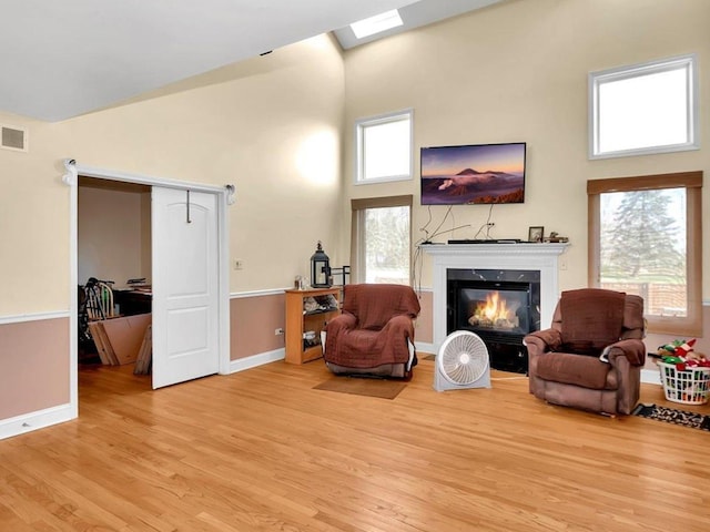 sitting room featuring a fireplace, a high ceiling, and light wood-type flooring