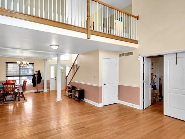 living room with decorative columns, light hardwood / wood-style flooring, and an inviting chandelier