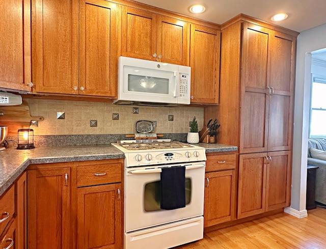 kitchen featuring decorative backsplash, light hardwood / wood-style floors, and white appliances