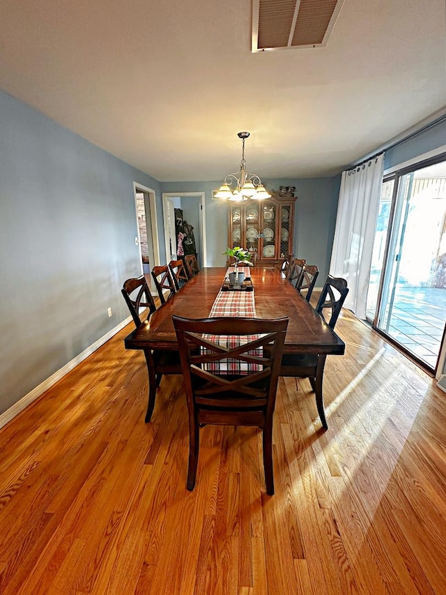 dining area featuring light wood-type flooring and an inviting chandelier