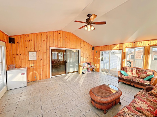 living room with light tile patterned floors, vaulted ceiling, ceiling fan, and wooden walls