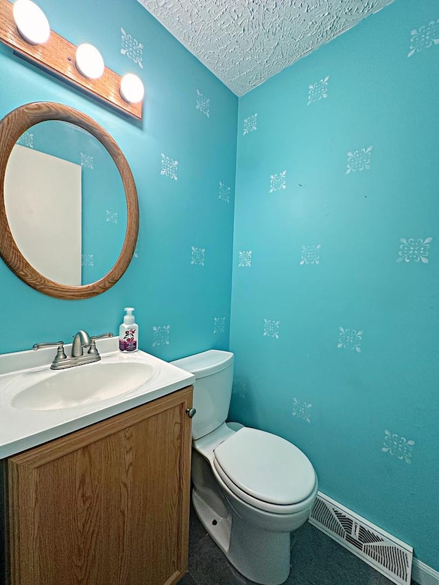 bathroom with vanity, toilet, and a textured ceiling