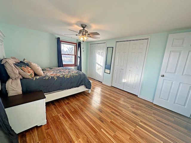 bedroom with hardwood / wood-style floors, ceiling fan, and multiple closets