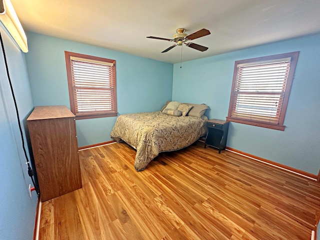 bedroom with ceiling fan, light wood-type flooring, and multiple windows