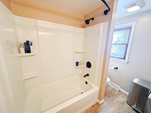 bathroom with shower / bathing tub combination, hardwood / wood-style floors, and toilet