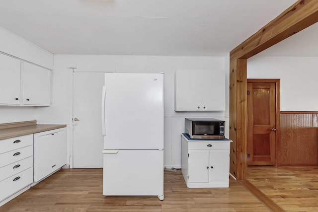 kitchen with white appliances, white cabinets, and light hardwood / wood-style flooring