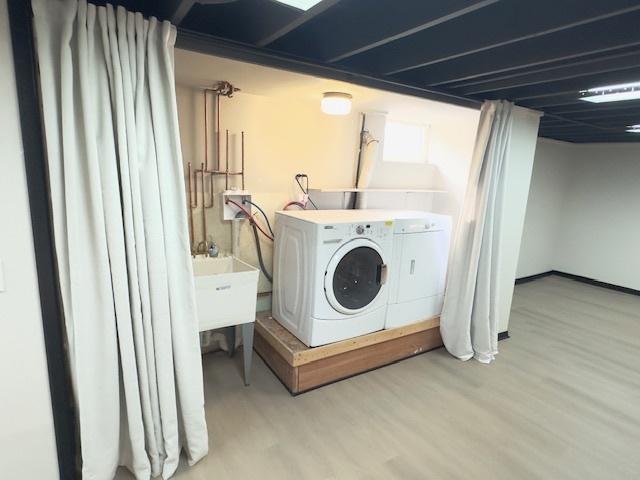 clothes washing area featuring sink, washer and dryer, and light hardwood / wood-style floors