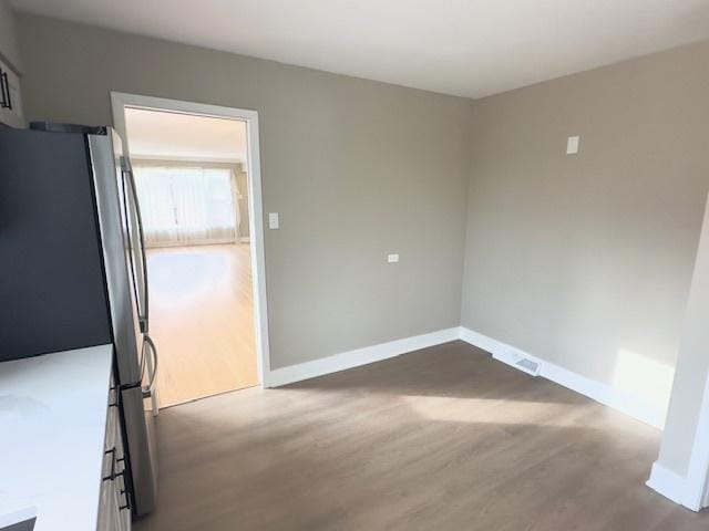 interior space featuring hardwood / wood-style floors, stainless steel fridge, and white cabinetry