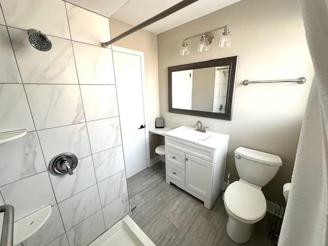 bathroom featuring toilet, vanity, and tiled shower