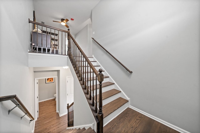 staircase with ceiling fan and hardwood / wood-style floors