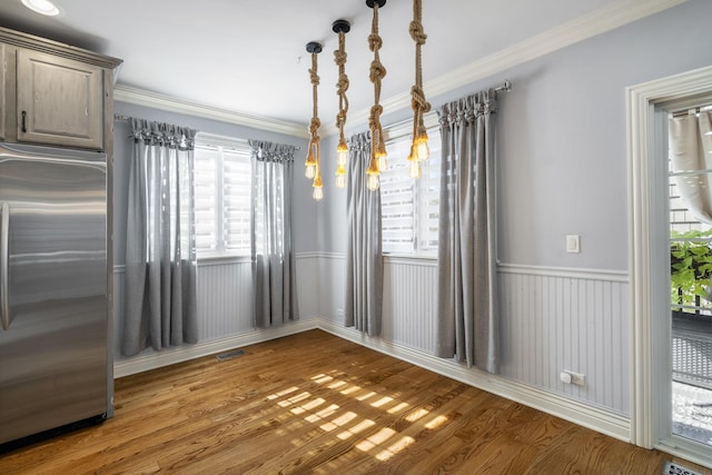 unfurnished dining area featuring hardwood / wood-style floors and crown molding