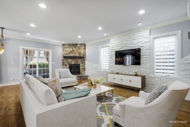 living room with dark hardwood / wood-style floors, a stone fireplace, and ornamental molding