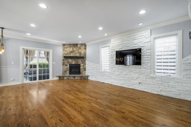 unfurnished living room featuring hardwood / wood-style flooring, a stone fireplace, and ornamental molding