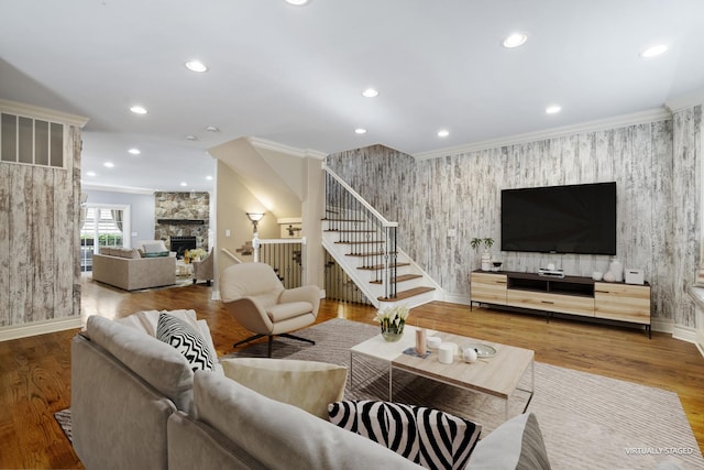 living room with wood-type flooring, a fireplace, and ornamental molding