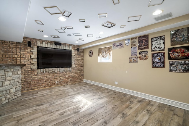 unfurnished living room featuring hardwood / wood-style floors and brick wall