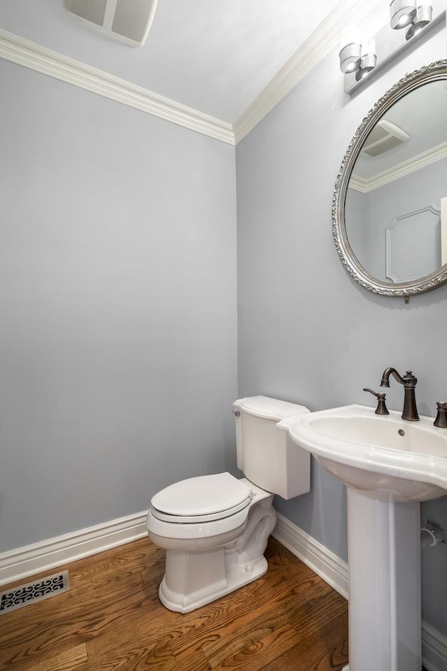 bathroom with hardwood / wood-style flooring, toilet, ornamental molding, and sink