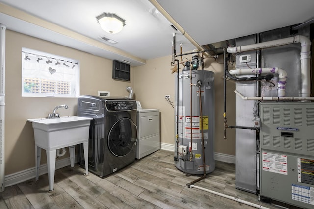 washroom featuring separate washer and dryer, hardwood / wood-style floors, gas water heater, and heating unit